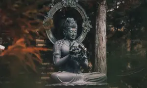 Posąg Buddy w medytacyjnej pozie, otoczony drzewami. Symbolizuje spokój i ścieżkę do oświecenia, czyli co to buddyzm.