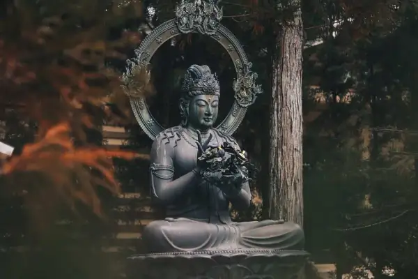 Posąg Buddy w medytacyjnej pozie, otoczony drzewami. Symbolizuje spokój i ścieżkę do oświecenia, czyli co to buddyzm.